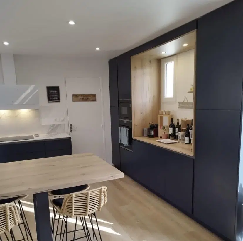 Découvrez notre nouvelle réalisation, une cuisine contemporaine qui excelle dans l'art d'allier l'esthétique à l'optimisation de l'espace. Le choix audacieux d'un bleu nuit profond pour les façades des meubles bas et des colonnes crée une atmosphère élégante et moderne, conférant une profondeur visuelle remarquable à l'ensemble. Cette teinte sophistiquée est parfaitement équilibrée par un plan de travail et une crédence clairs, apportant luminosité et contrastes subtils, tout en assurant une surface pratique et facile d'entretien.