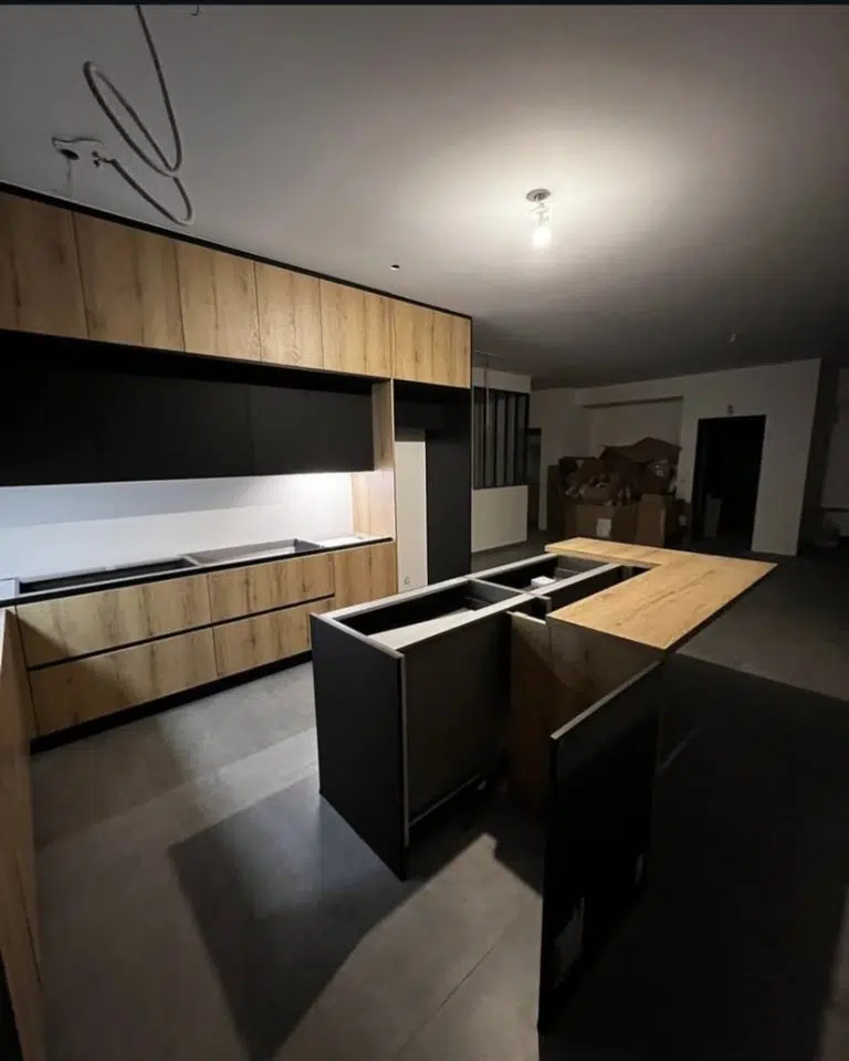 Découvrez notre dernière création, une cuisine sur mesure qui incarne l'équilibre parfait entre l'authenticité du bois et la modernité du noir mat. Pensée pour les intérieurs contemporains, cette réalisation allie des façades chaleureuses en chêne à l'élégance intemporelle du noir matte. Chaque élément a été conçu pour optimiser l'espace et la fonctionnalité : un îlot central multifonctionnel invitant à la convivialité et simplifiant la préparation, des rangements intelligents et des tiroirs coulissants intégrés pour une ergonomie optimale. Plus qu'une cuisine, c'est un véritable espace de vie où design épuré, matériaux de qualité et praticité se conjuguent pour créer une atmosphère unique et raffinée.