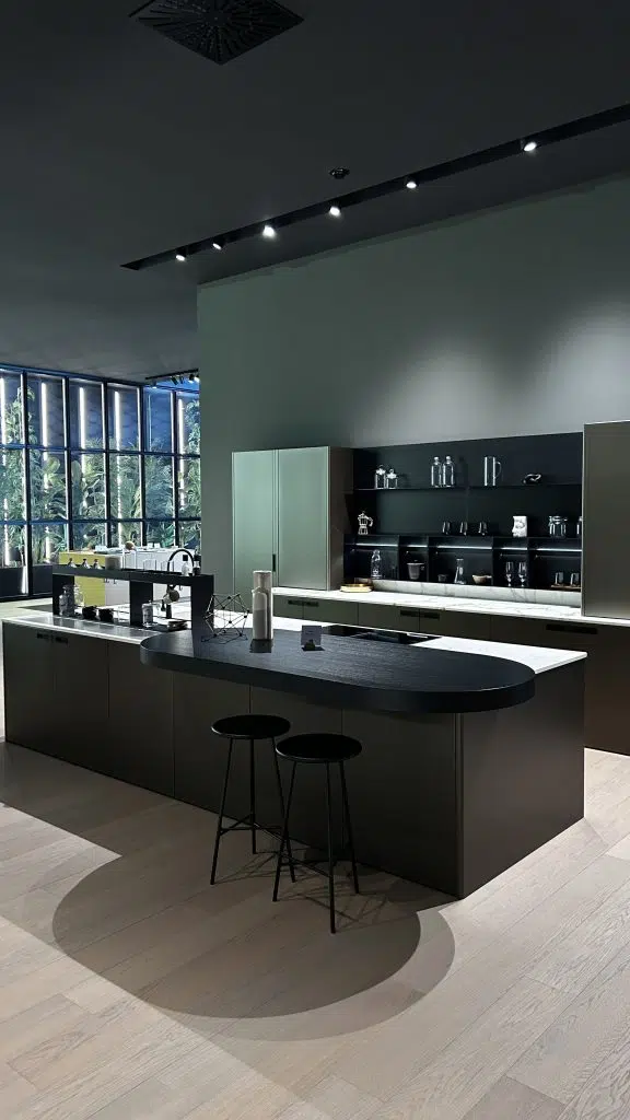 Découvrez une vision avant-gardiste de la cuisine, tirée directement du showroom de l'un de nos prestigieux fournisseurs italiens. Cette composition illustre parfaitement l'élégance du design contemporain avec ses lignes épurées, ses matériaux mats et ses contrastes subtils. L'îlot central bicolore, doté d'une extension organique, et les éléments hauts intégrés, offrent une fonctionnalité optimisée sans compromis sur l'esthétique. Chez Bodezign, nous nous inspirons de ces tendances pour concevoir votre cuisine sur mesure, un espace à la fois fonctionnel, raffiné et unique.